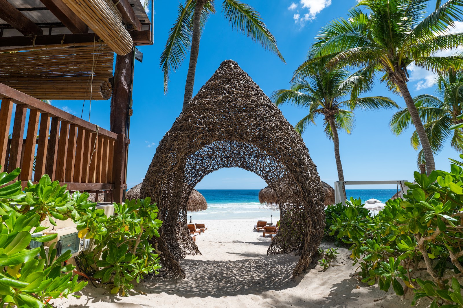 Woven arch sculpture framing the beach at Ana y José Beach Club