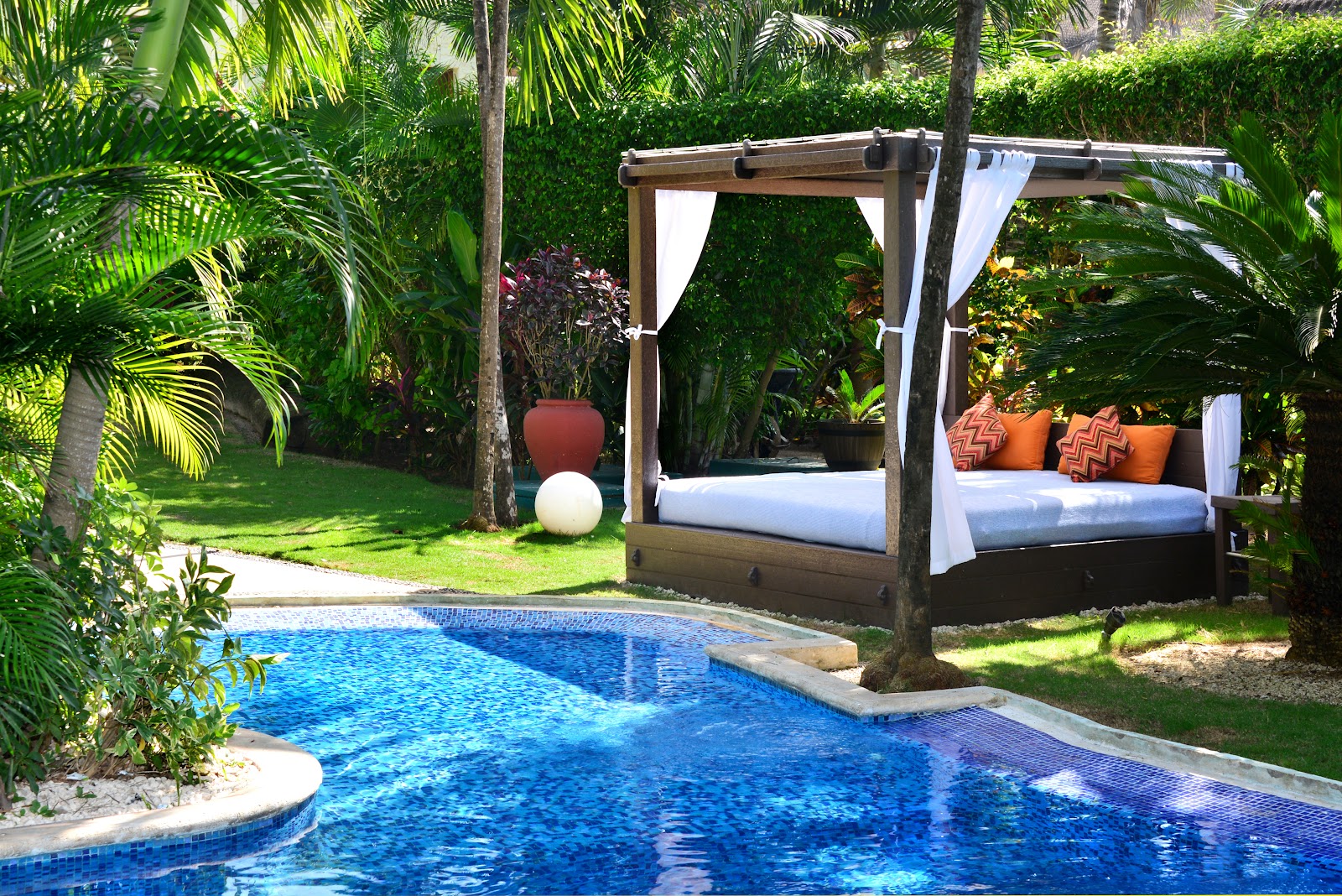 Canopy daybed with orange cushions beside the pool at Ana y José