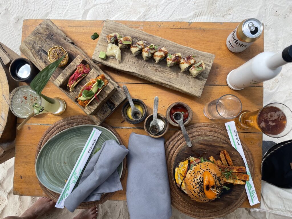 Table spread of sushi, tacos and grilled seafood dishes
