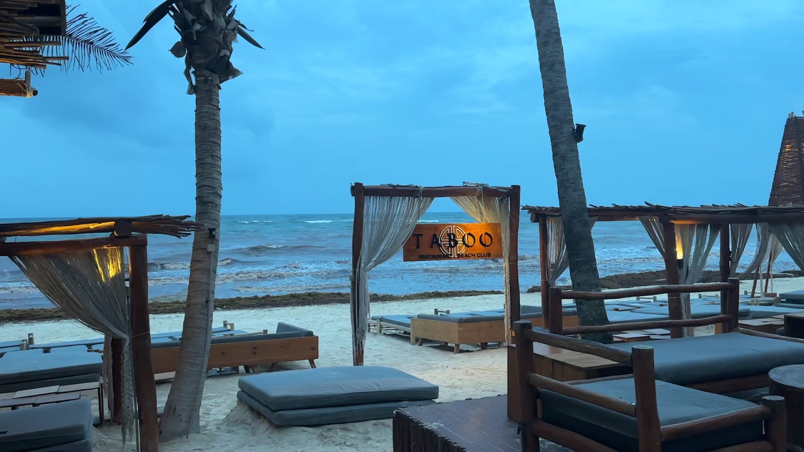 Beach loungers facing the Caribbean Sea at dusk