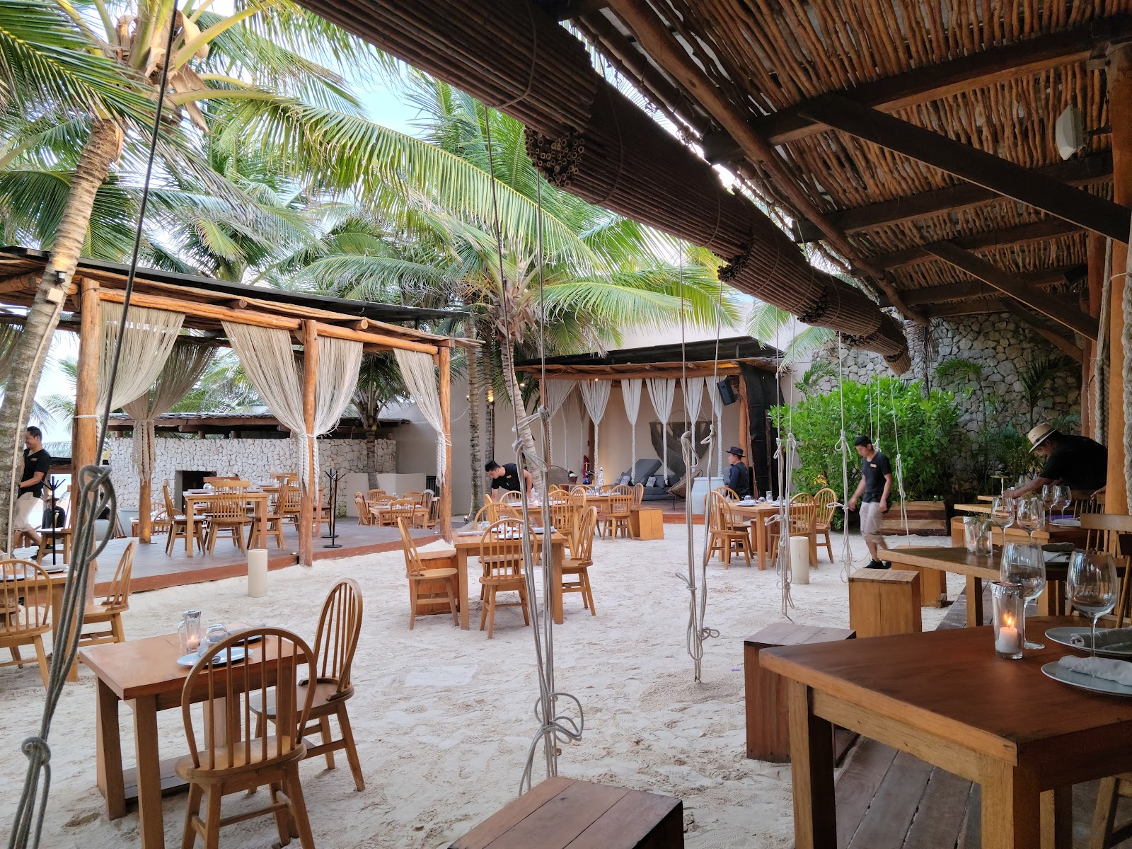 Beachfront dining area shaded by palapa roofs