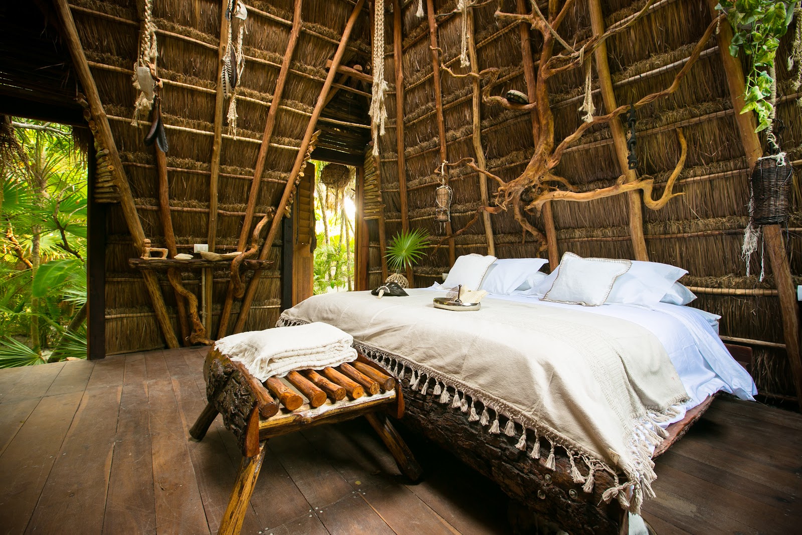 Bed under a thatched roof with jungle views