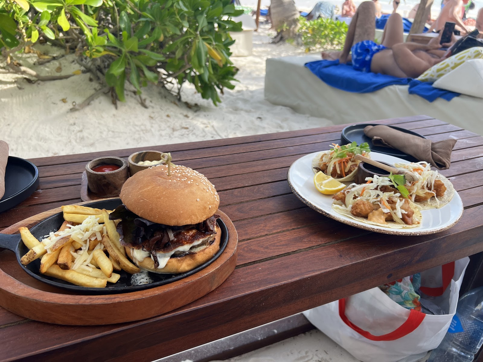 Burger and tacos served at a beachside table