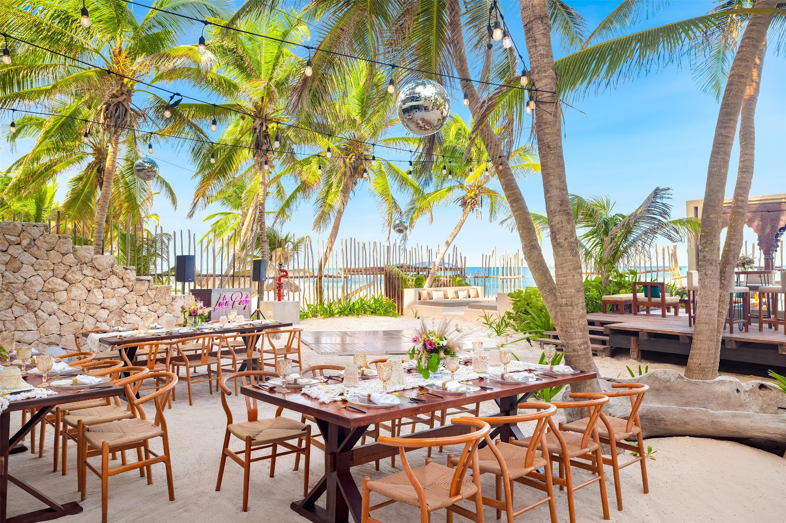 Beachfront dining area shaded by palm trees at Casa Zamna Beach Club