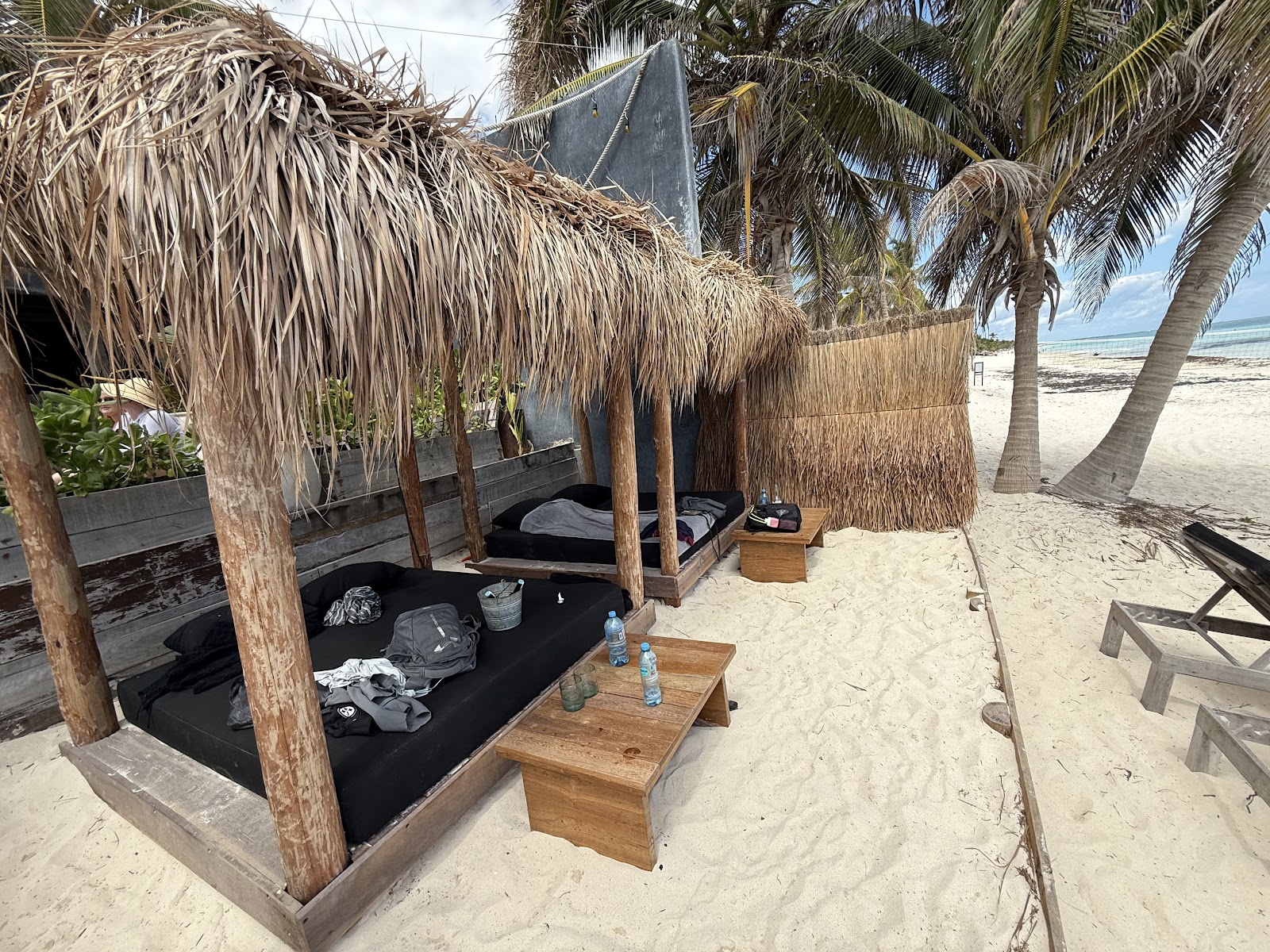 Cushioned loungers under a thatched palapa
