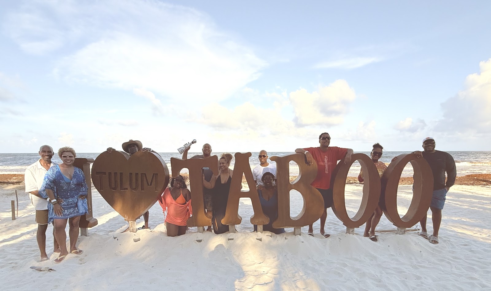 Group celebrating with Taboo letter balloons on the beach