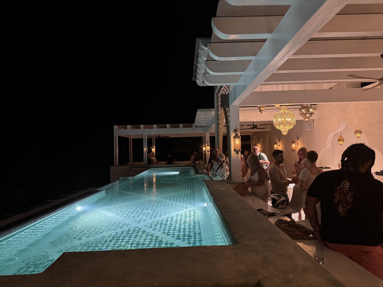 Guests gathered by the illuminated pool at night