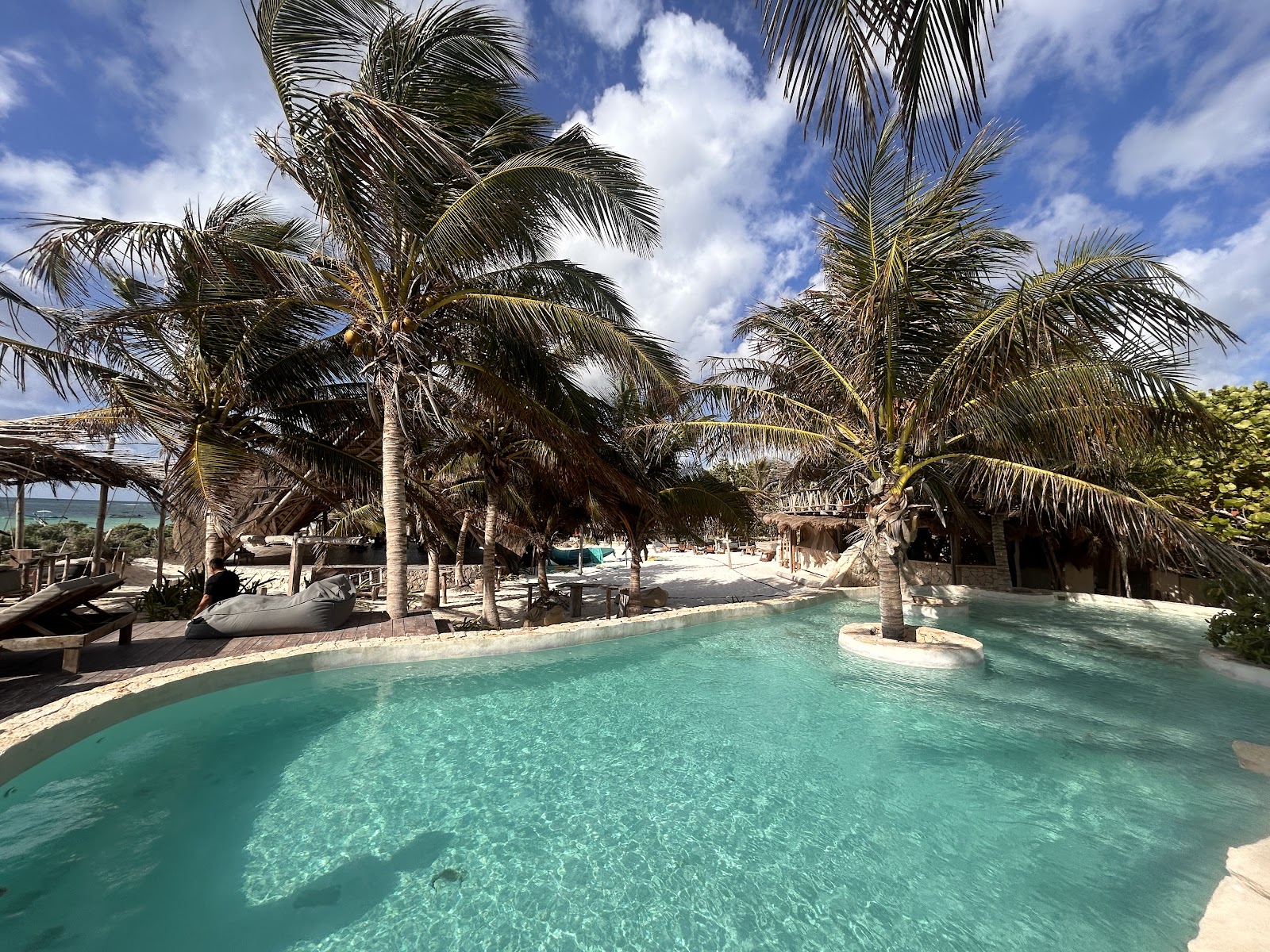 Pool surrounded by palm trees at IKAL Tulum