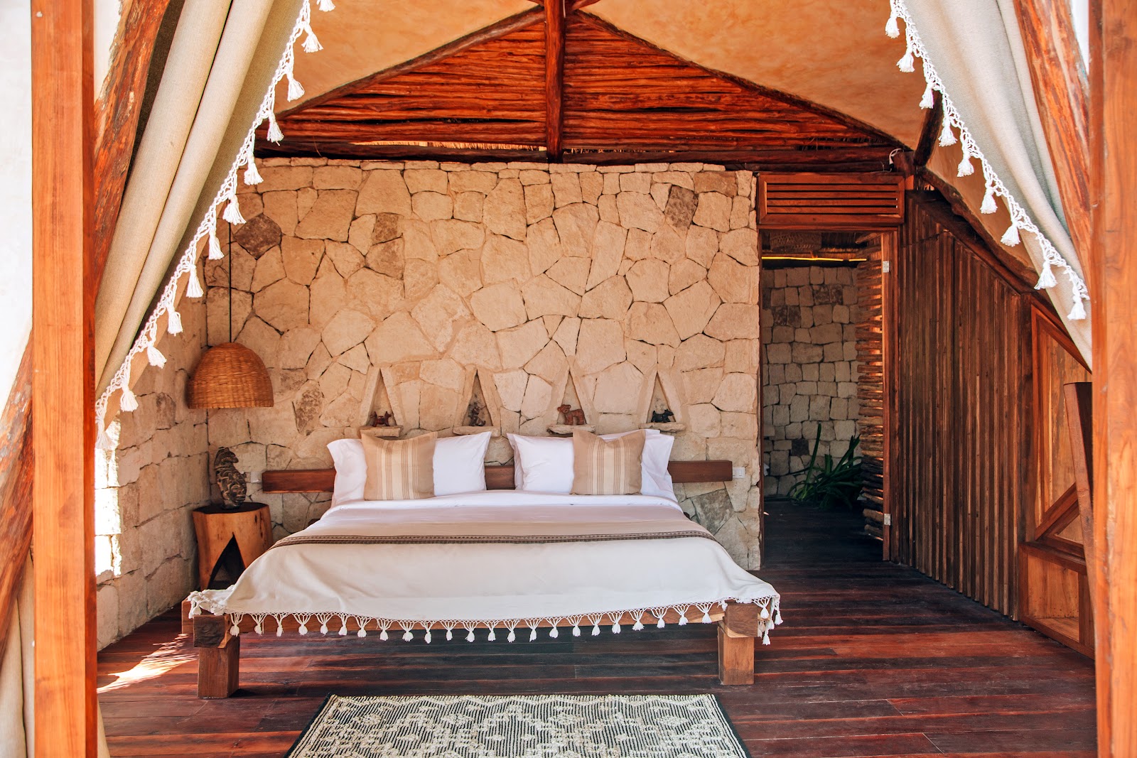 Suite with stone walls and a canopy bed at IKAL Tulum