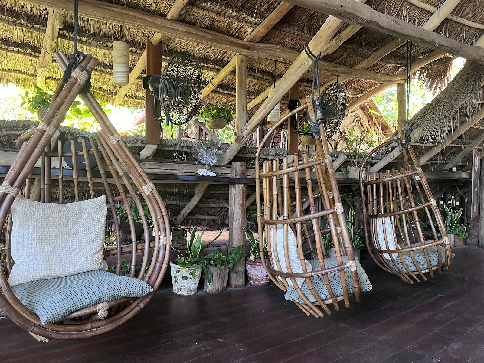 Hanging rattan chairs under a palapa at Kanan Tulum