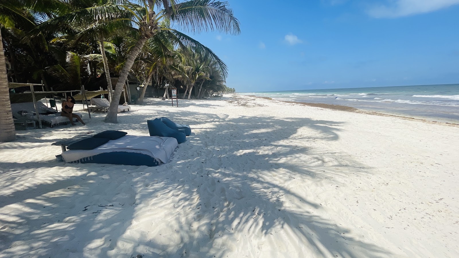 Loungers on white sand beside turquoise water