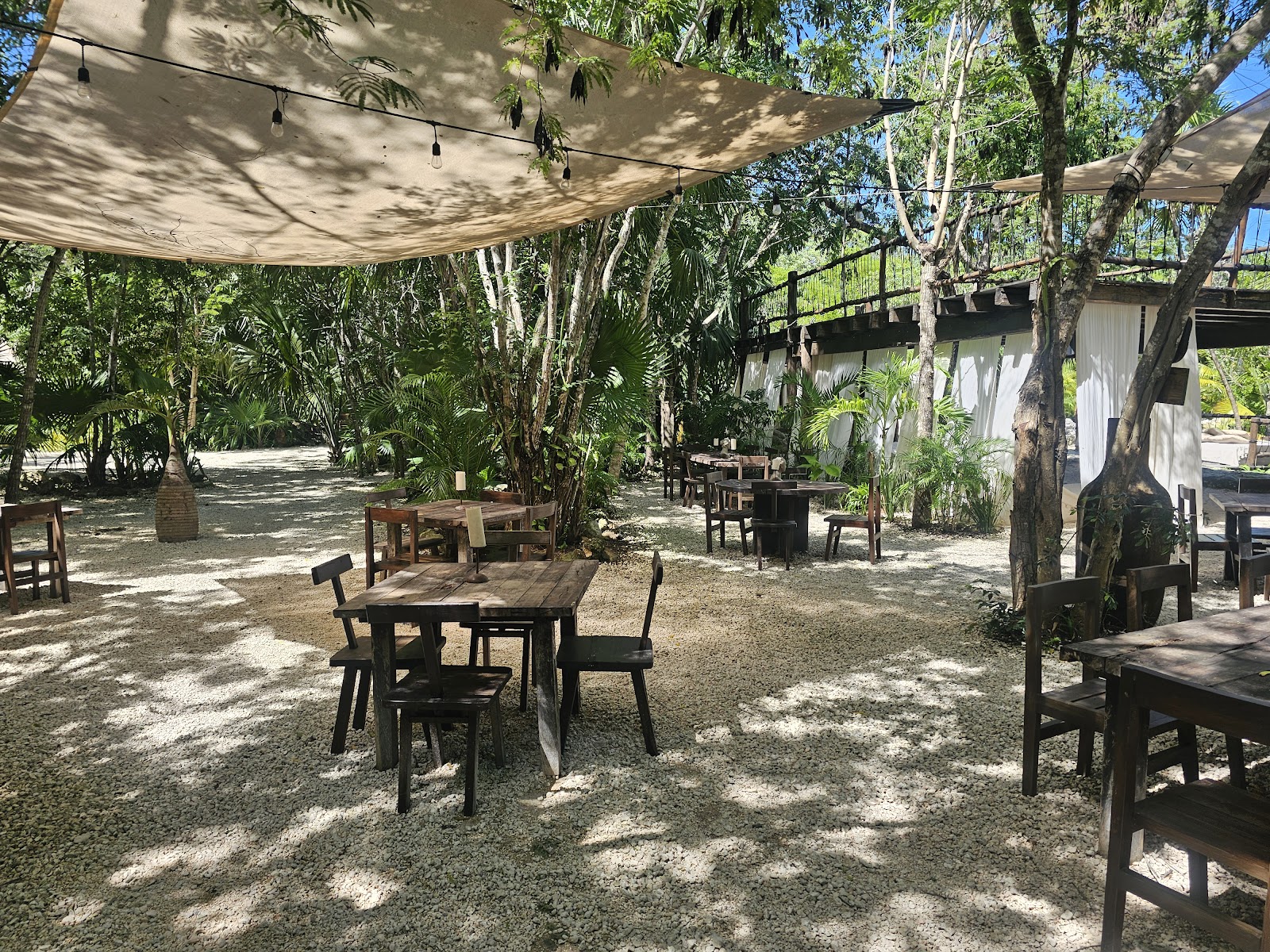 Outdoor dining tables under a shade sail