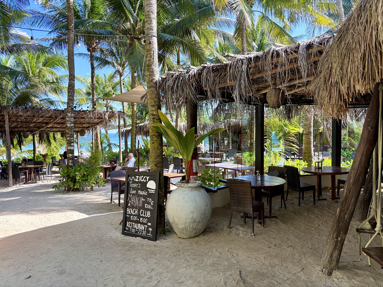 Palapa-covered restaurant entrance with a chalkboard menu