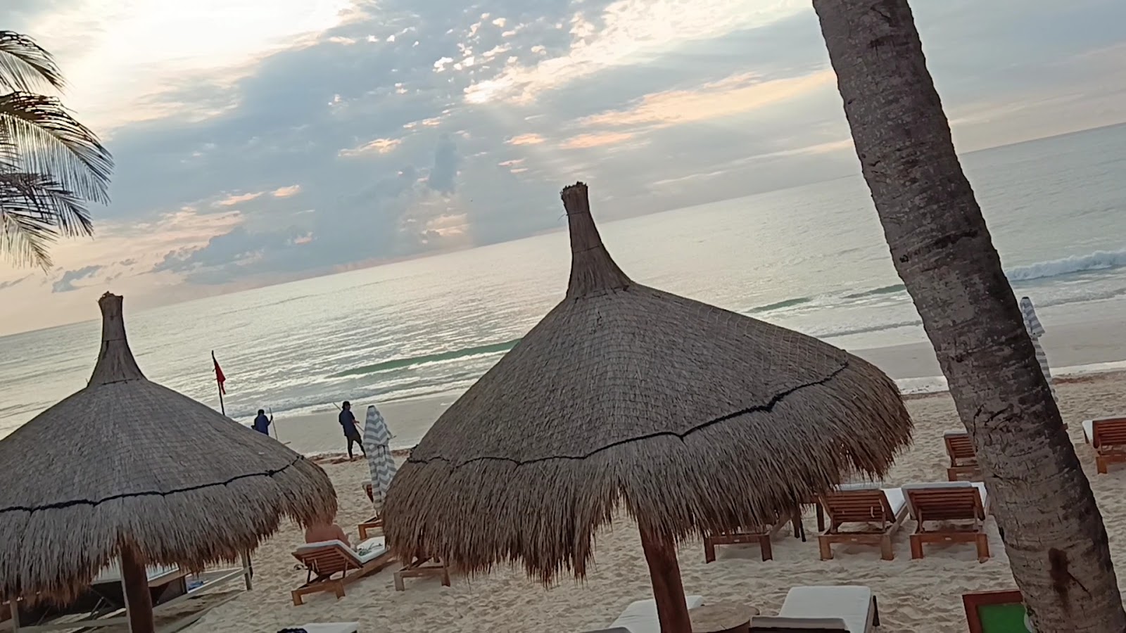 Palapa umbrellas on Tulum beach at sunset