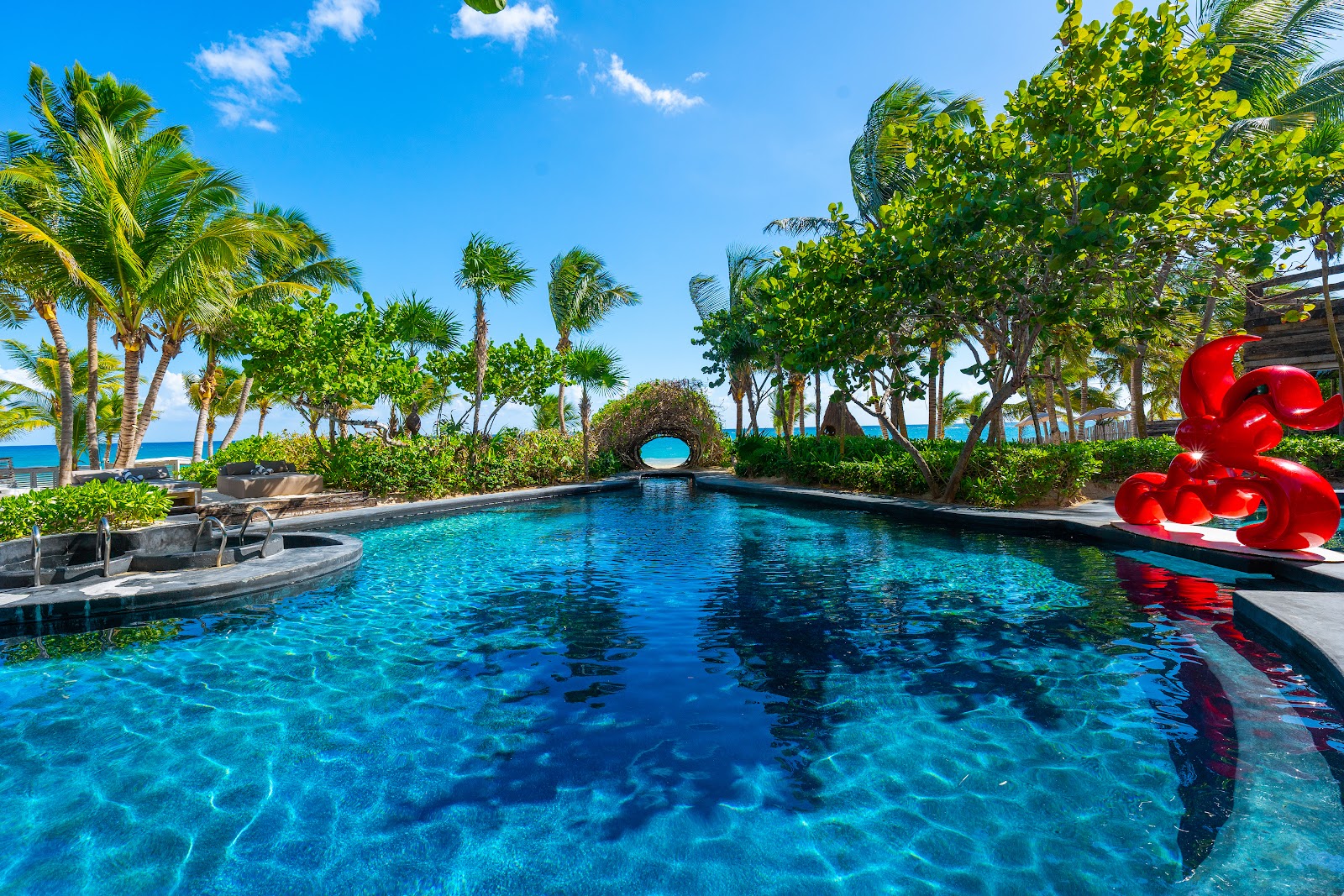 Pool with a red sculpture surrounded by palm trees