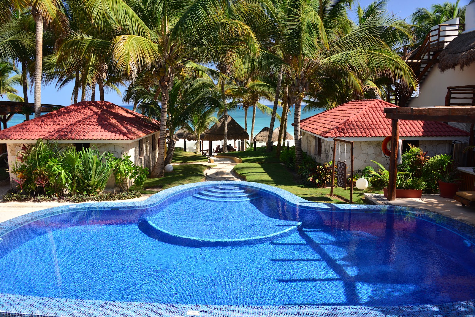 Swimming pool surrounded by tropical gardens and red-roofed villas