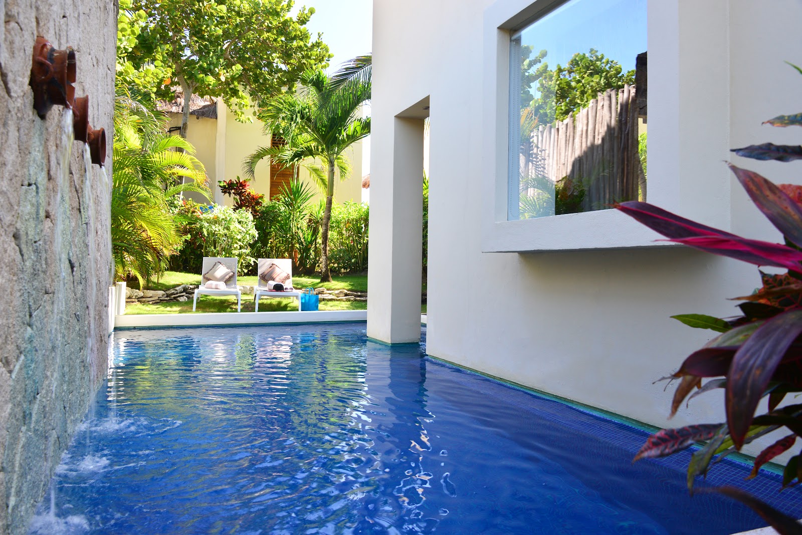 Pool running alongside tropical plants and garden villas