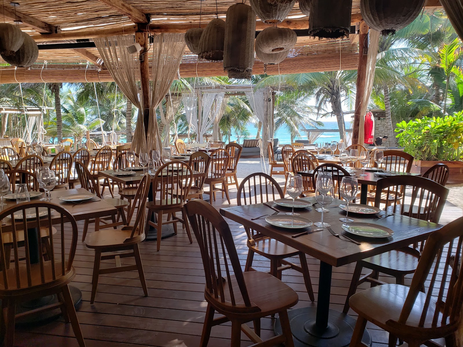 Restaurant tables set up under a thatched roof