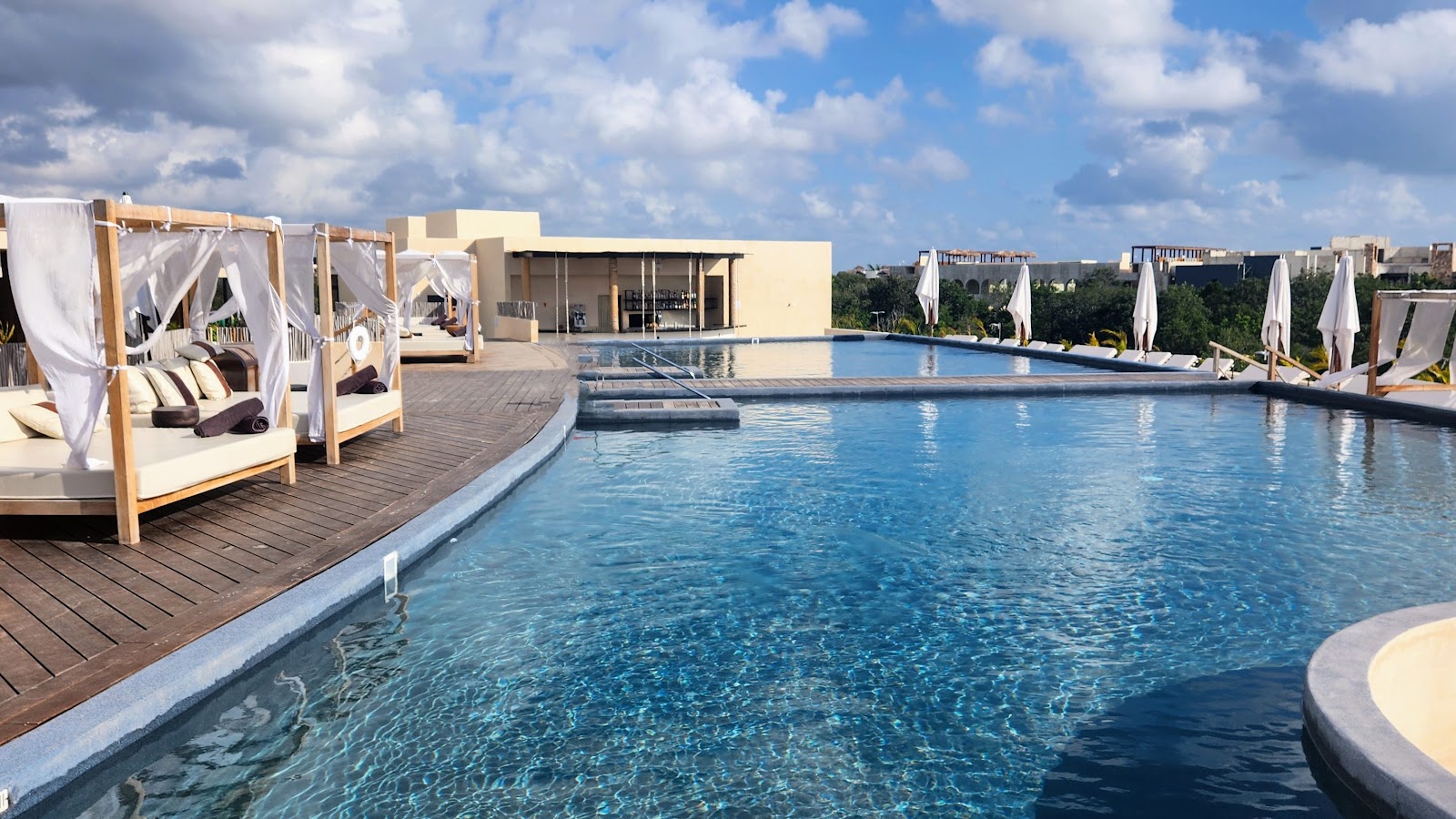 Canopy daybeds lining the infinity pool at Secrets Tulum