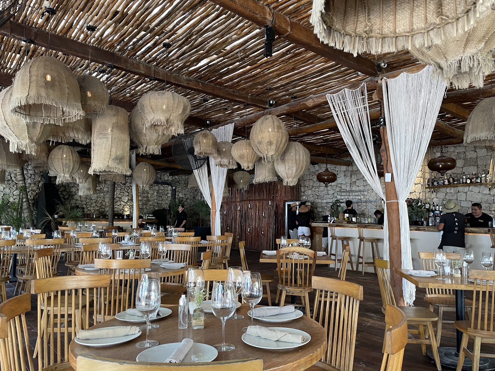 Rattan lanterns and white curtains in the Taboo Tulum dining room