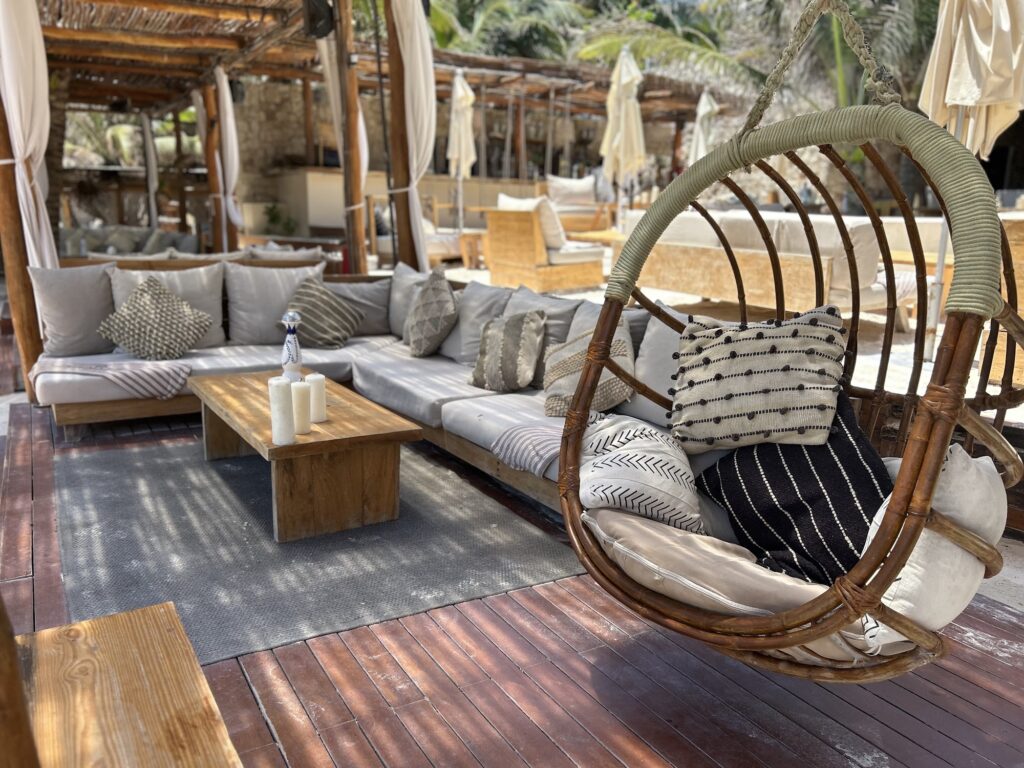 Bohemian lounge with a rattan hanging chair and cushioned sofas at Tantra