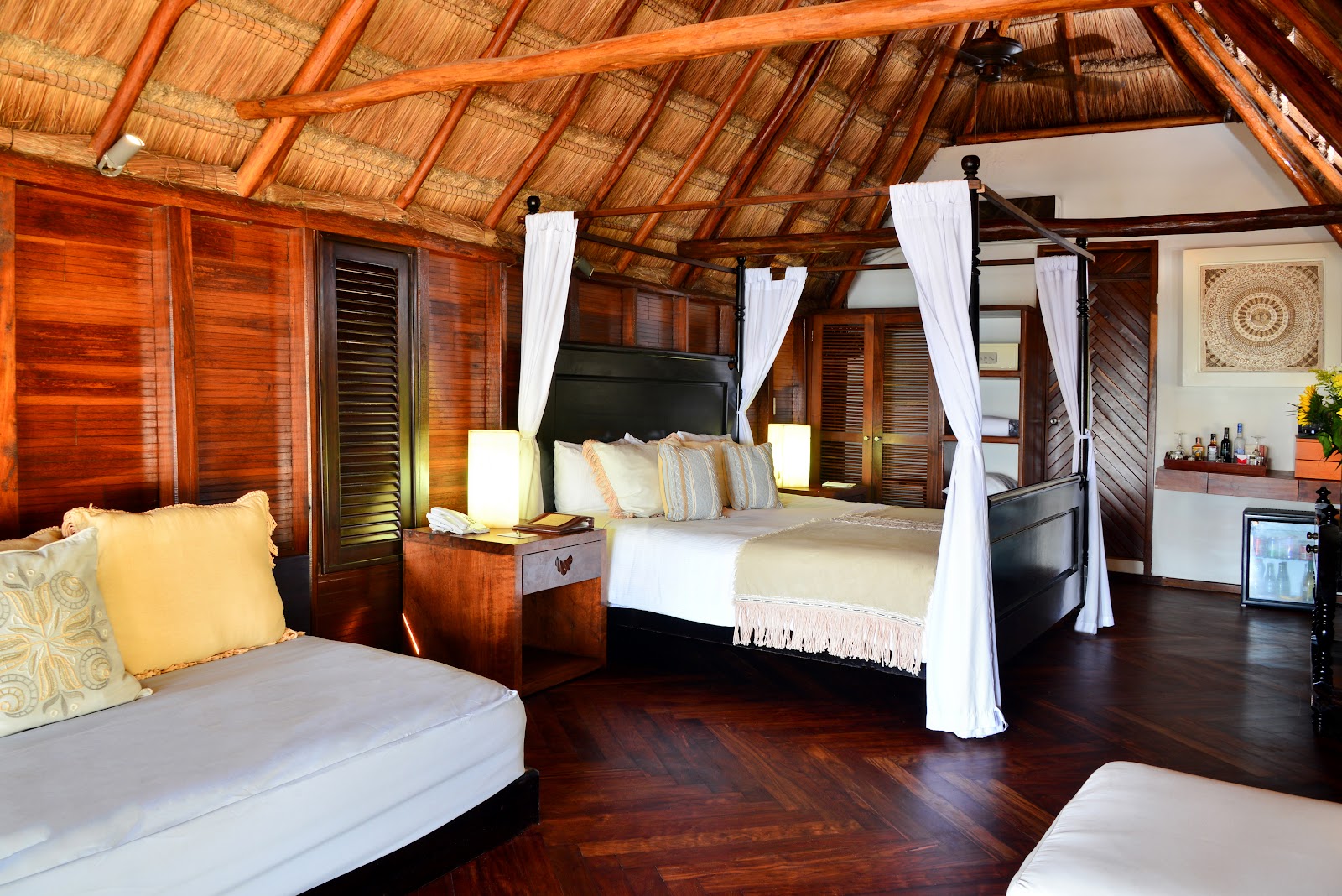Thatched-roof suite with canopy bed and lounge sofa