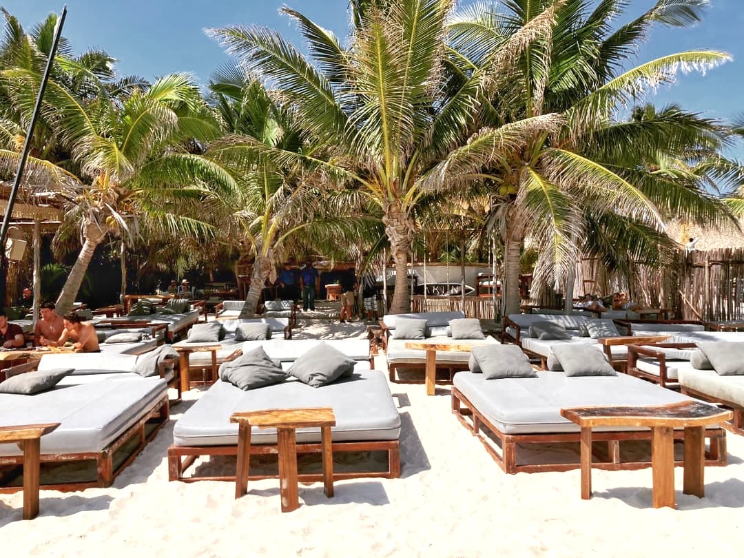 Tulumania beach club daybeds under palm trees