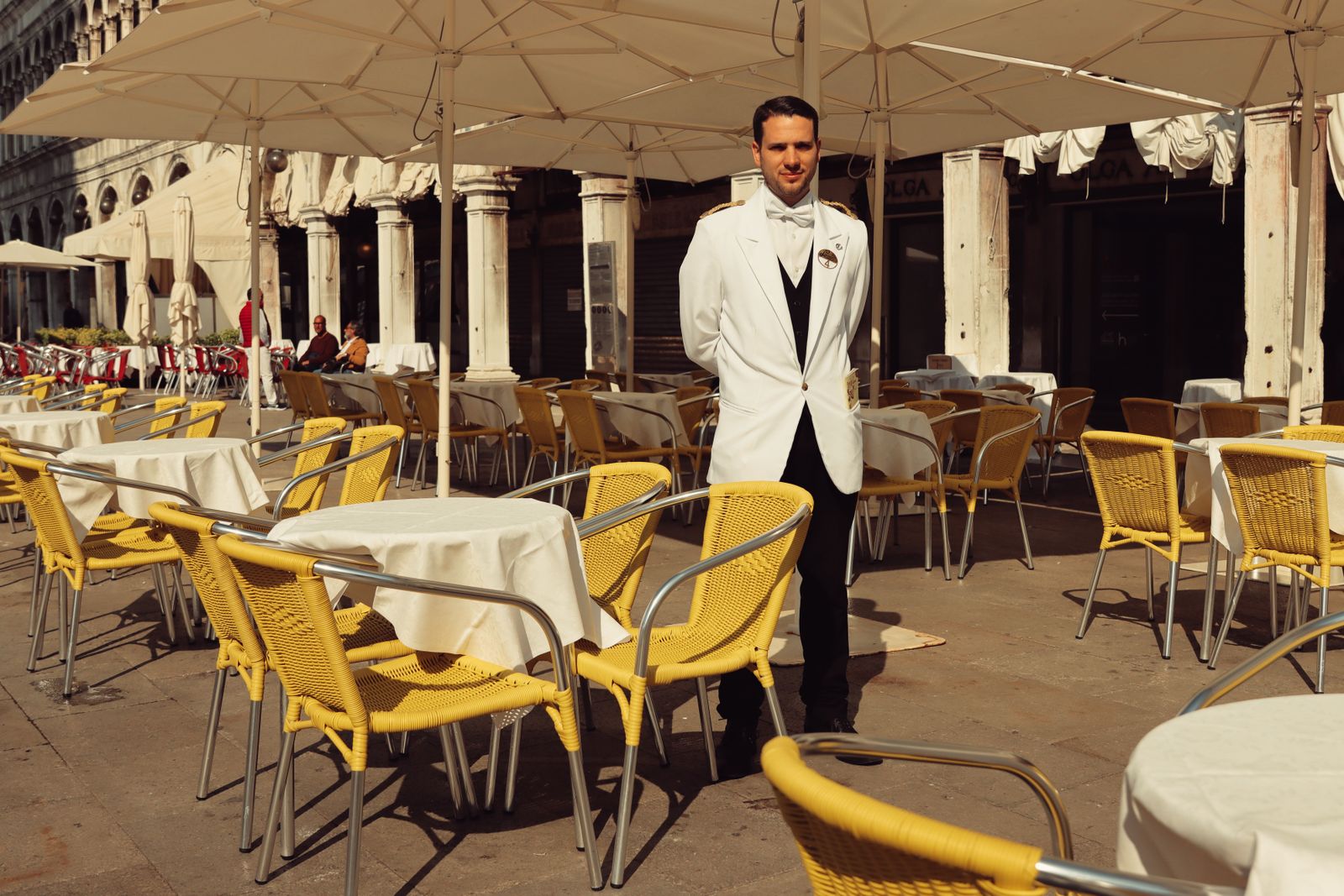Waiter in a white suit standing in an outdoor restaurant