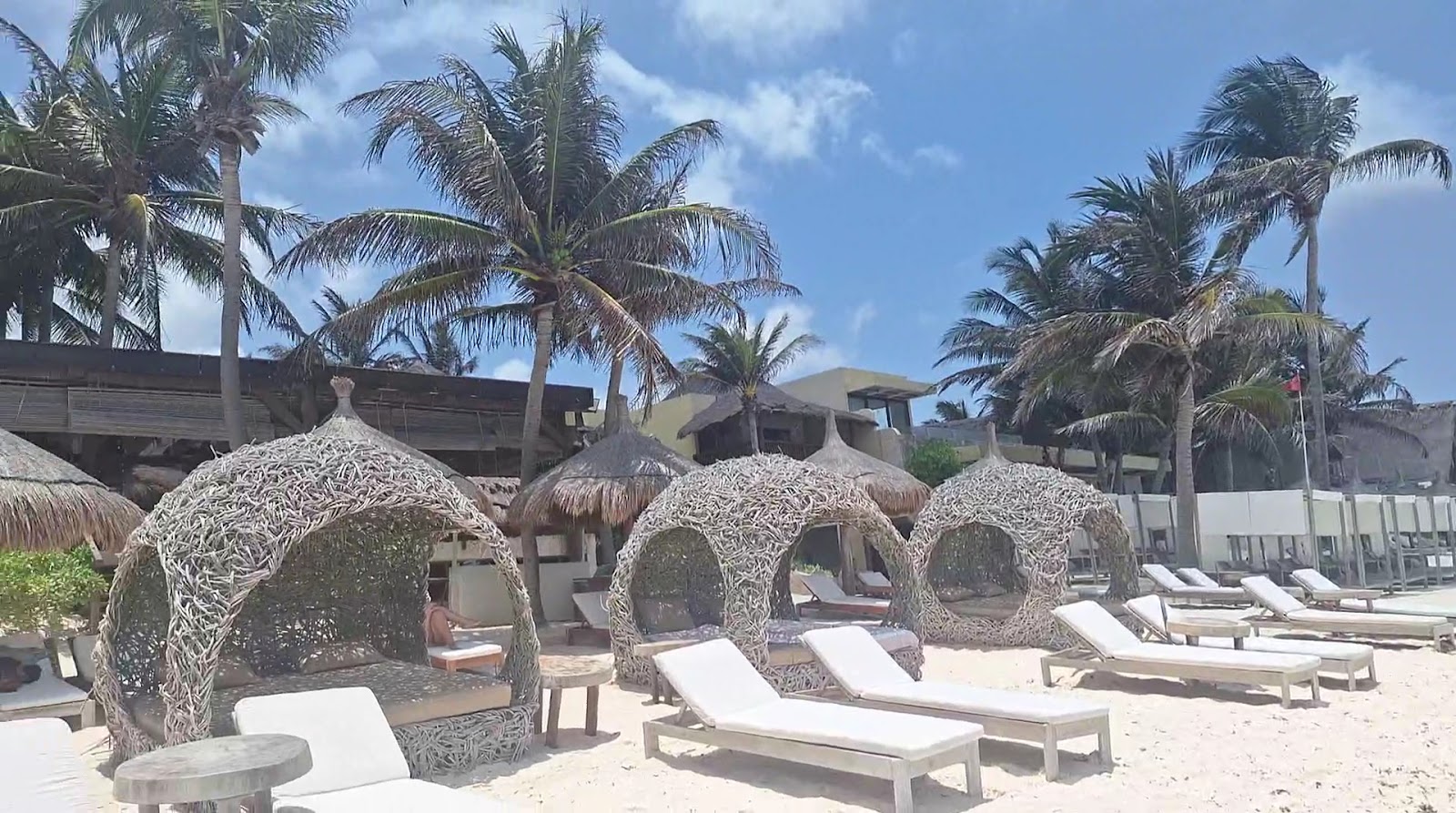 Woven nest loungers and white sunbeds on the beach in Tulum