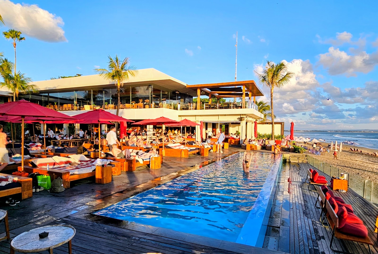 Pool deck with red umbrellas overlooking Seminyak beach