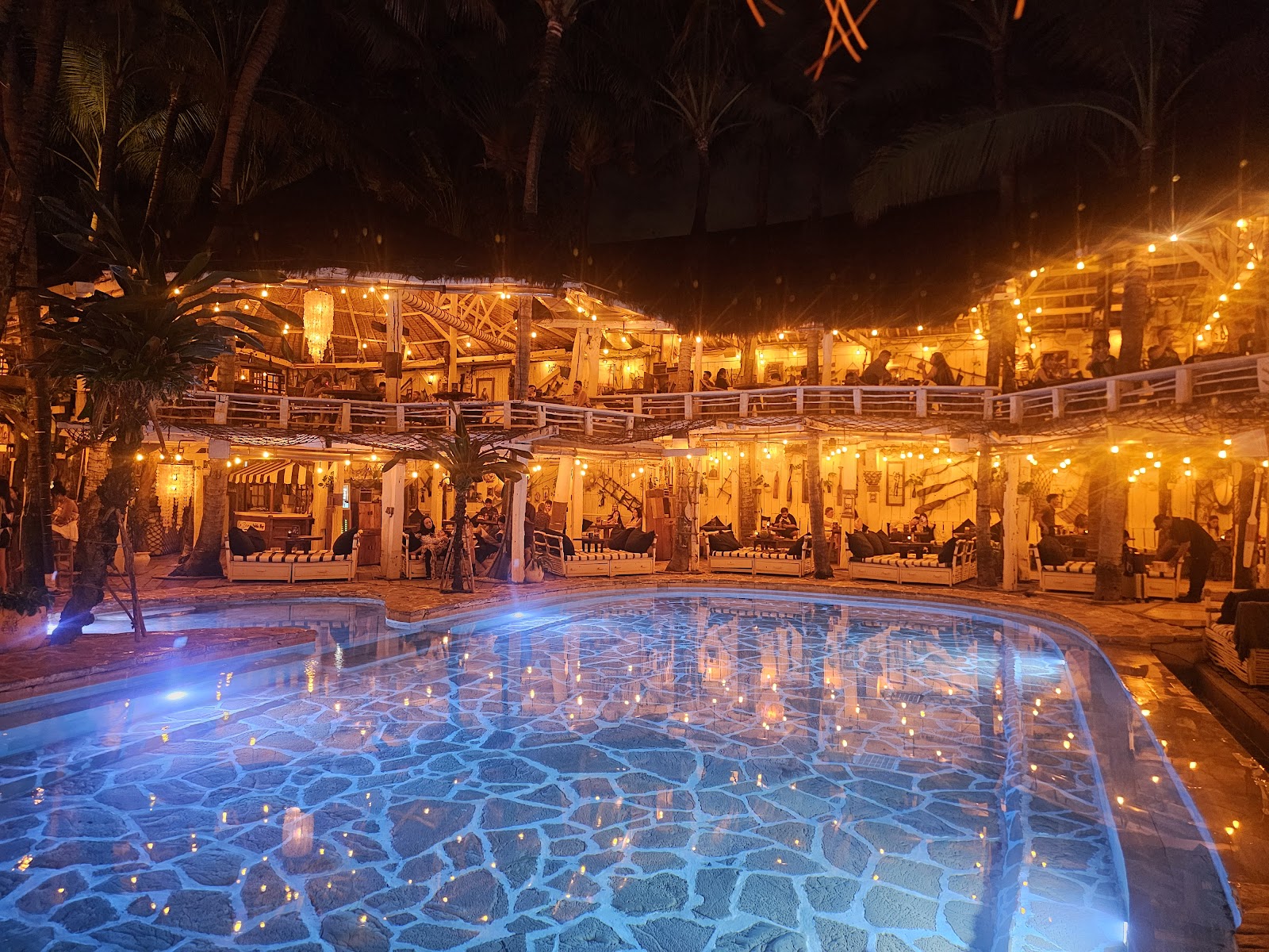 Pool glowing at night surrounded by rustic wooden decor