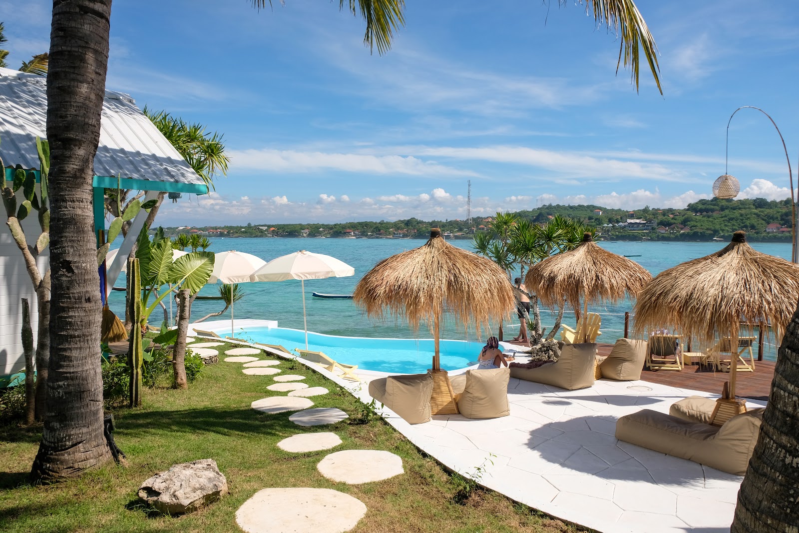 Pool with thatched umbrellas and colourful beach huts at Le Pirate Nusa Ceningan
